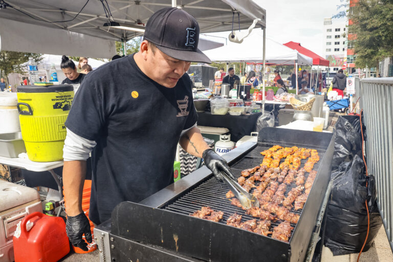 A vendor grilling skewers of meat at a food booth during Celebrate Lunar