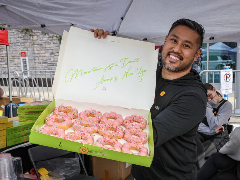 A vendor holding open a box of pink Lunar New Year doughnuts at Celebrate Lunar
