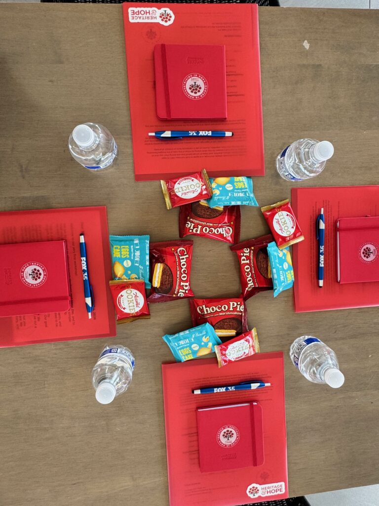 Workshop table set with Heritage and Hope journals, pens and snacks for arriving students