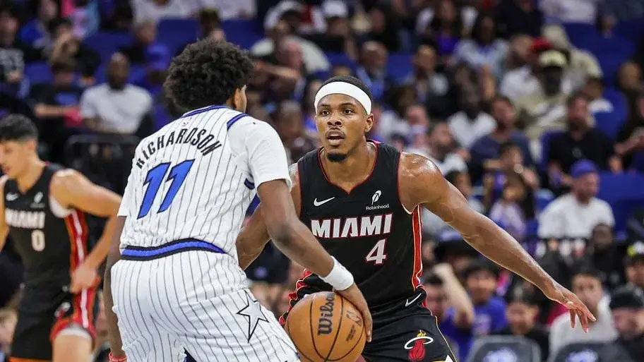 Orlando Magic player brings the ball up against a Miami Heat defender in front of a full crowd
